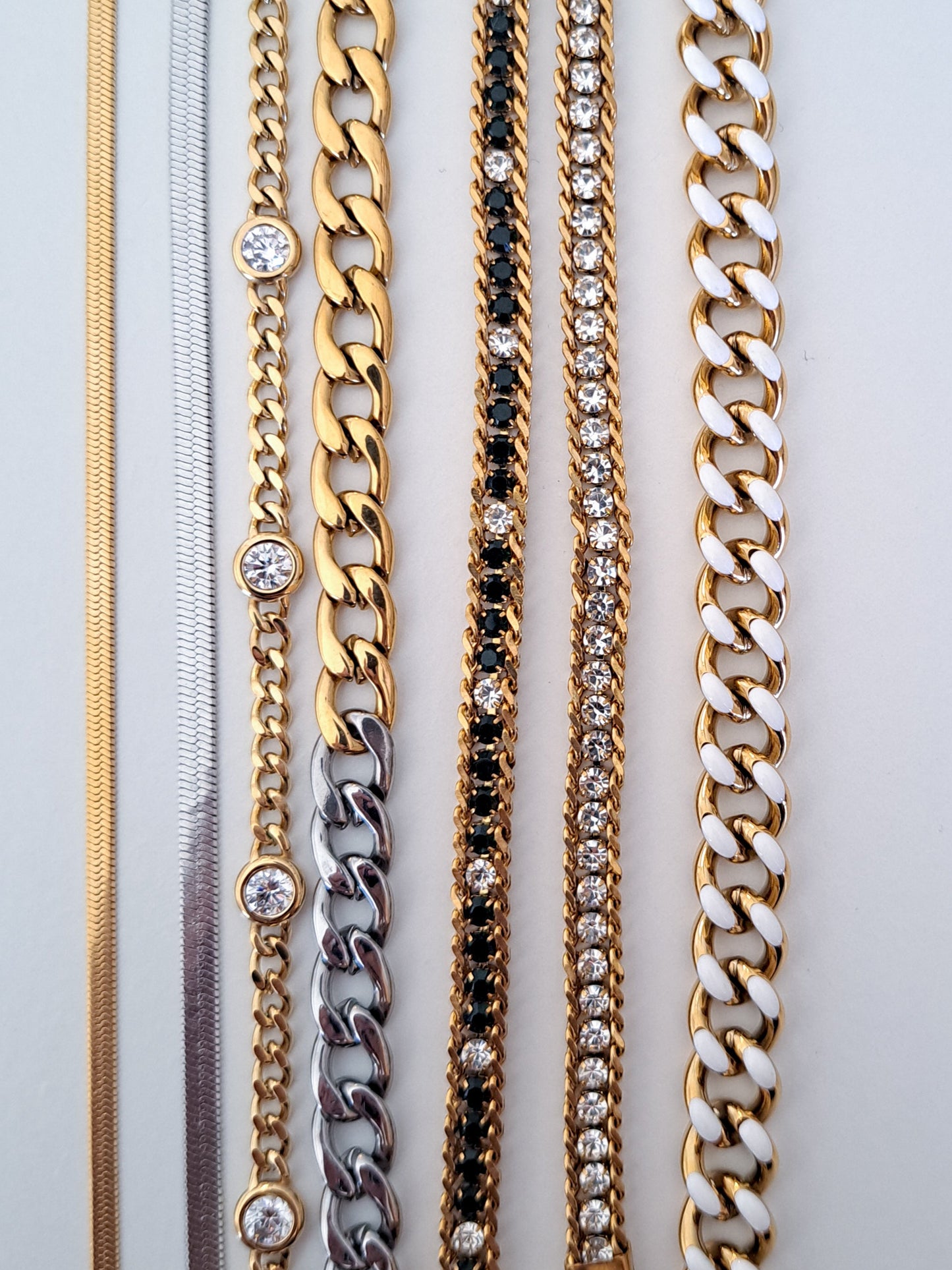 Collection of gold and silver chain necklaces on a light gray background