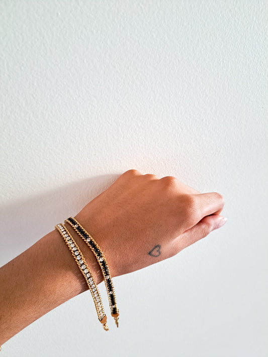 Hand wearing multiple gold bracelets on a white background