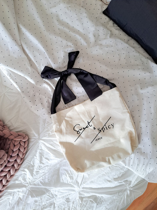 Canvas tote bag with satin black bow as shoulder strap. 