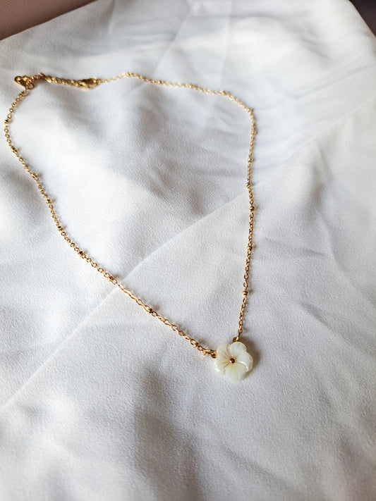 white flower pendant on a dainty gold beaded chain necklace 