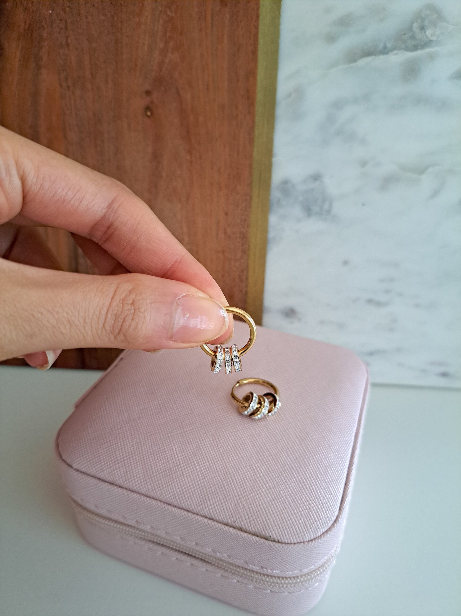 woman holding gold hoop earrings with diamond rings in them 